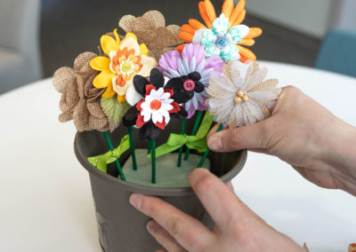 hands placing flower buttons in pot