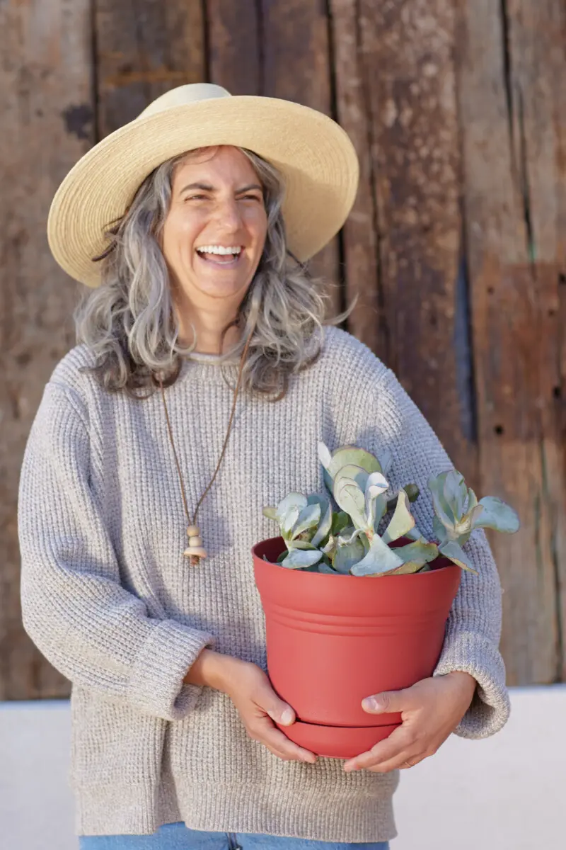 blonde woman holding potted plant